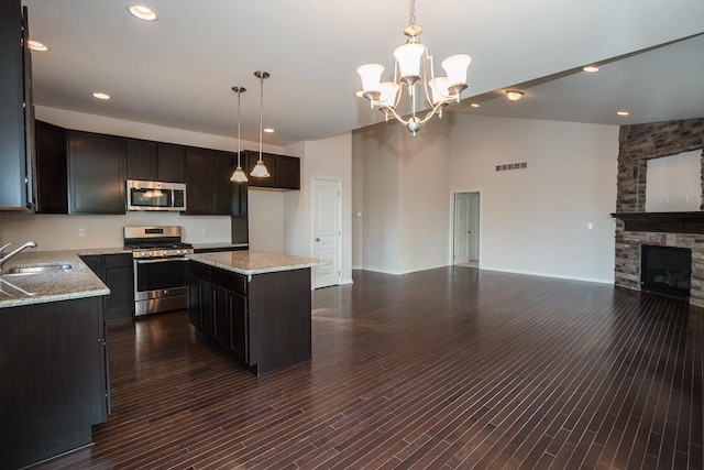 kitchen featuring visible vents, open floor plan, stainless steel appliances, a stone fireplace, and a sink