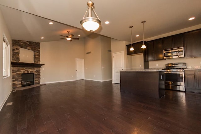 kitchen with appliances with stainless steel finishes, dark wood-type flooring, a fireplace, and dark brown cabinets