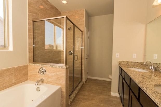 full bath with double vanity, a sink, a bath, and a shower stall