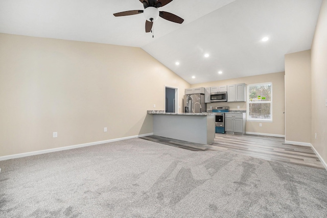 unfurnished living room featuring vaulted ceiling, light colored carpet, and ceiling fan