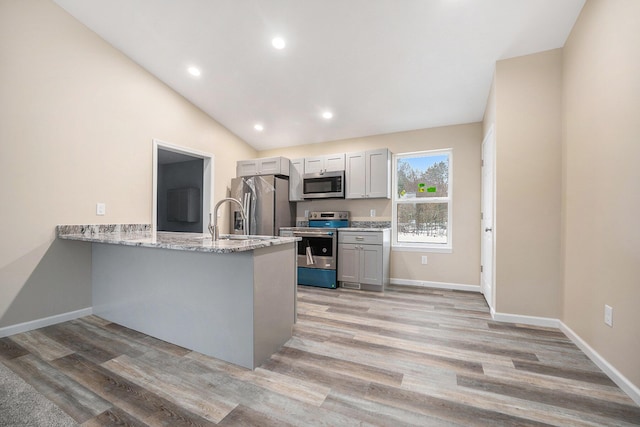 kitchen with vaulted ceiling, white cabinets, light hardwood / wood-style floors, kitchen peninsula, and stainless steel appliances