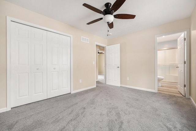 unfurnished bedroom with ceiling fan, light colored carpet, ensuite bath, and a closet