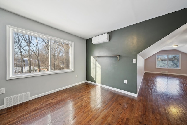 bonus room with an AC wall unit and dark hardwood / wood-style floors