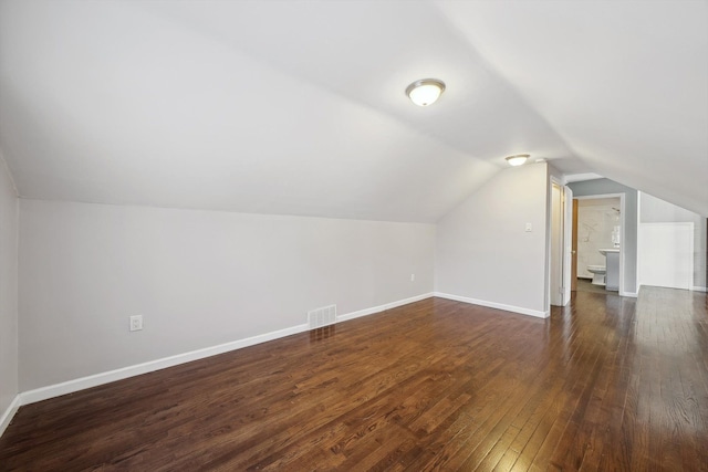 bonus room with dark wood-type flooring and vaulted ceiling