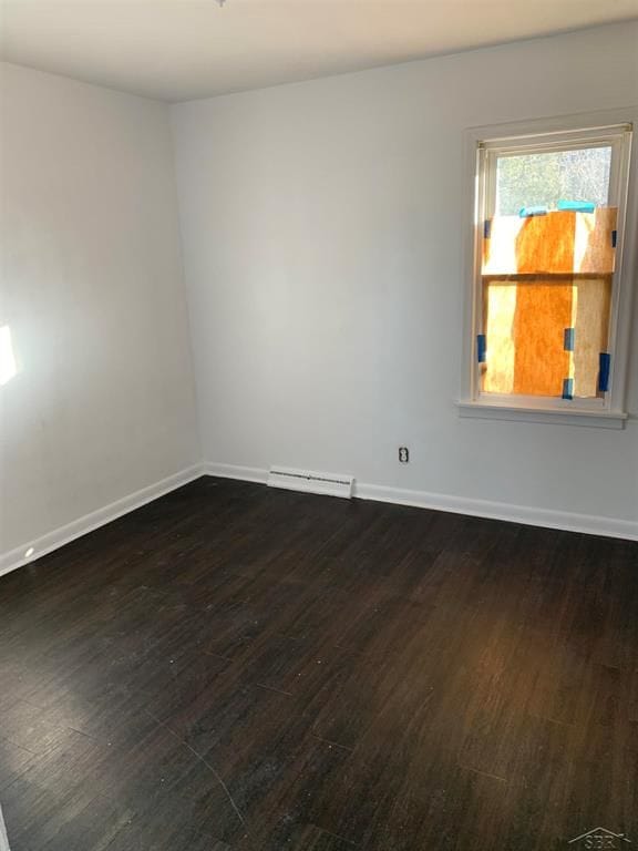 unfurnished room with dark wood-type flooring and baseboard heating