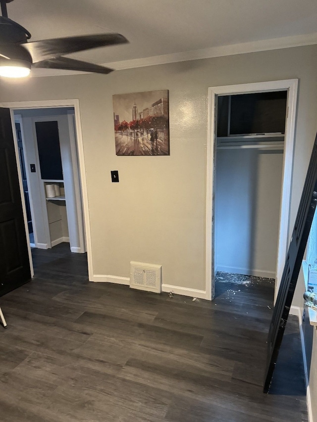 unfurnished bedroom with crown molding, dark wood-type flooring, ceiling fan, and a closet