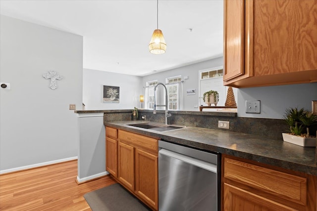 kitchen with dishwasher, sink, light wood-type flooring, and decorative light fixtures