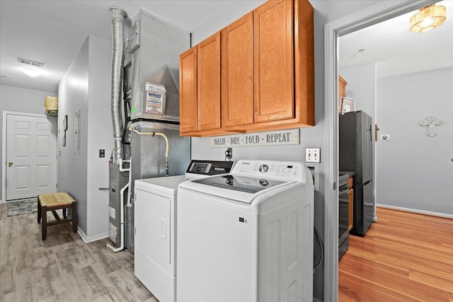 laundry room with cabinets, separate washer and dryer, and light wood-type flooring