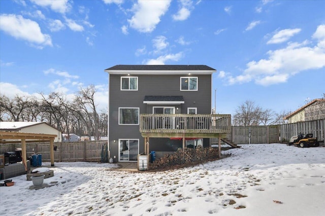 snow covered rear of property with a deck