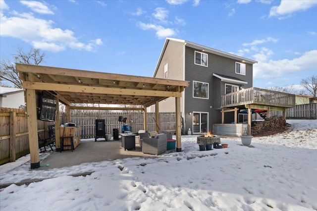 snow covered house featuring a wooden deck and an outdoor living space with a fire pit