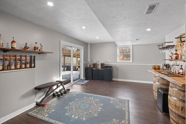 bar with dark wood-type flooring and a textured ceiling