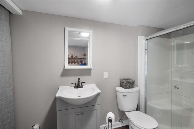 bathroom featuring a shower with door, vanity, and toilet