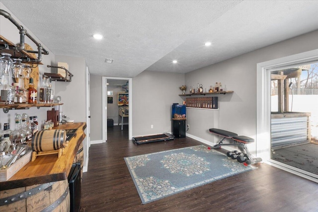 interior space with dark wood-type flooring, bar area, and a textured ceiling