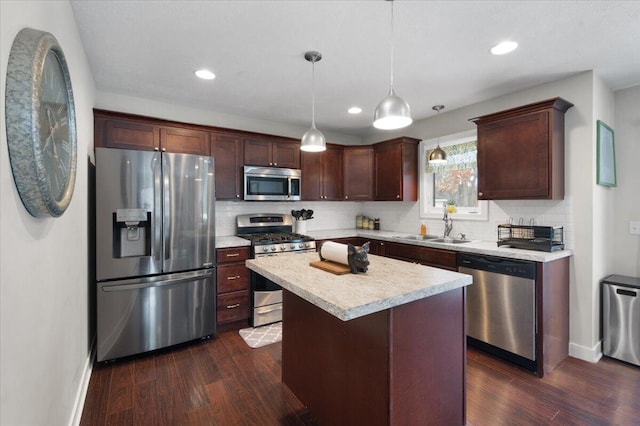 kitchen with sink, dark wood-type flooring, hanging light fixtures, stainless steel appliances, and a kitchen island