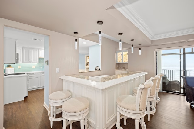 kitchen featuring decorative light fixtures, white cabinetry, ornamental molding, kitchen peninsula, and dark wood-type flooring