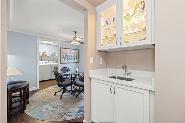 kitchen featuring sink, separate washer and dryer, dark hardwood / wood-style floors, ceiling fan, and white cabinets