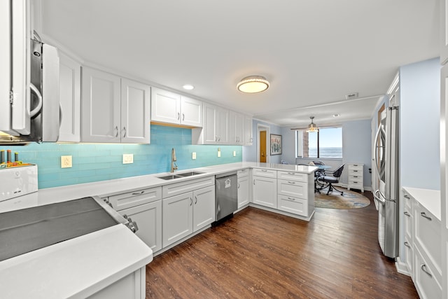 kitchen with sink, white cabinets, kitchen peninsula, stainless steel appliances, and dark wood-type flooring