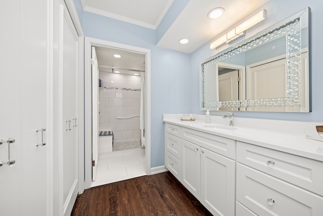 bathroom with ornamental molding, vanity, wood-type flooring, and a tile shower