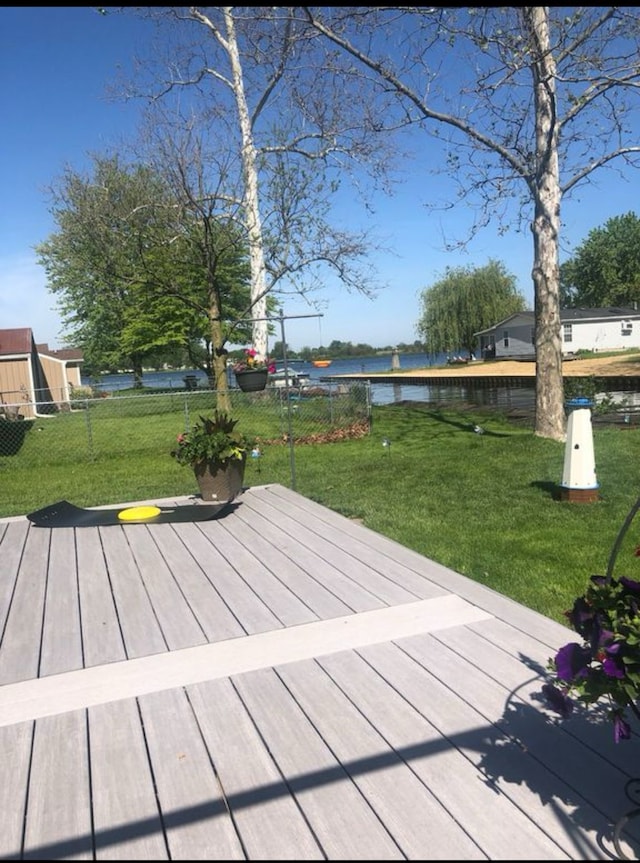 deck with a water view and a lawn