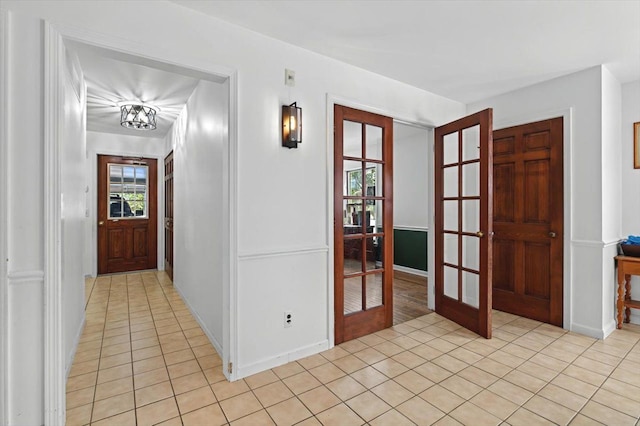 hallway with light tile patterned floors, french doors, and baseboards