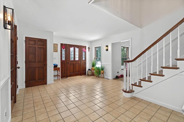foyer entrance featuring light tile patterned floors, a wealth of natural light, and stairs