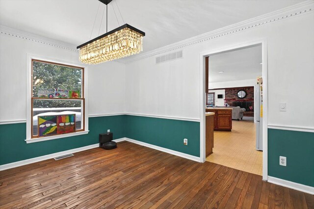 unfurnished room featuring ornamental molding, an inviting chandelier, and wood-type flooring