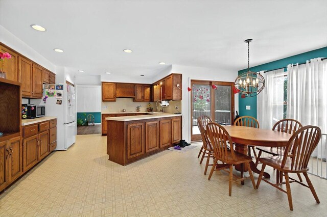 kitchen with a notable chandelier, white fridge with ice dispenser, and hanging light fixtures