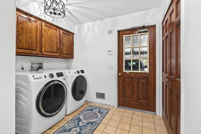 laundry area with light tile patterned flooring, washer and dryer, and cabinets