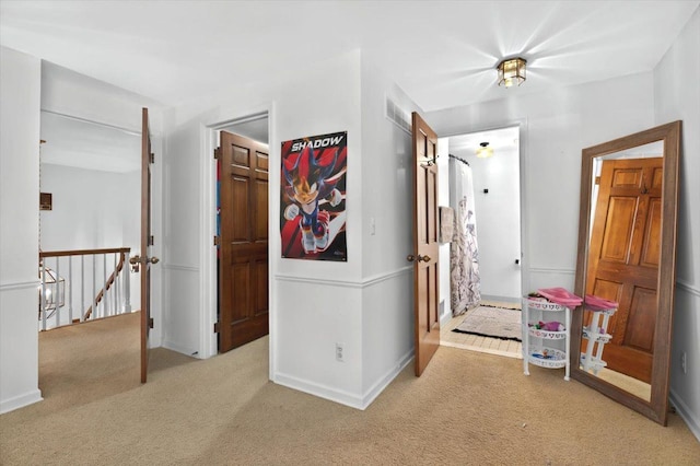 hallway featuring visible vents, baseboards, an upstairs landing, and carpet
