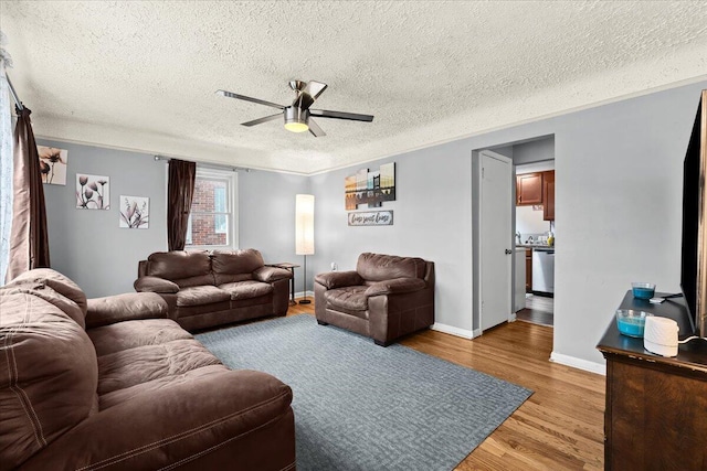 living room featuring crown molding, a textured ceiling, light hardwood / wood-style flooring, and ceiling fan