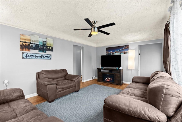 living room with hardwood / wood-style flooring, ceiling fan, crown molding, and a textured ceiling