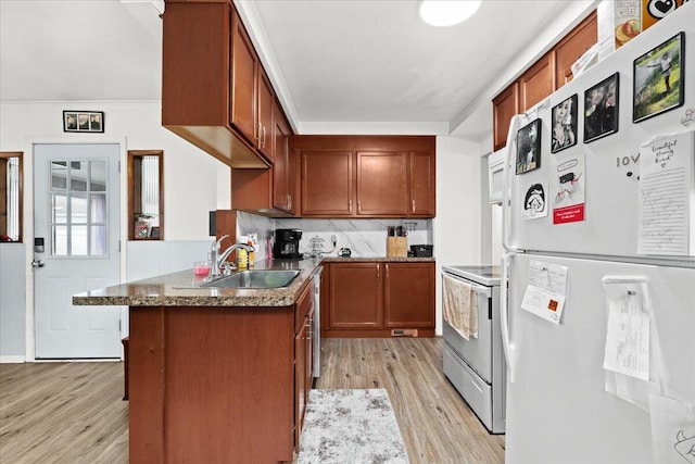 kitchen featuring sink, kitchen peninsula, white appliances, light hardwood / wood-style floors, and decorative backsplash