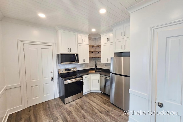 kitchen with appliances with stainless steel finishes, tasteful backsplash, white cabinetry, wood-type flooring, and wooden ceiling