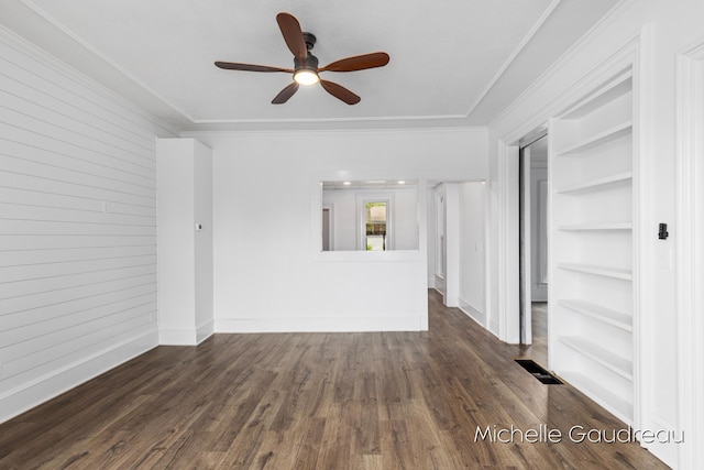 unfurnished living room featuring built in shelves, ceiling fan, ornamental molding, and dark hardwood / wood-style flooring