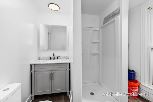 bathroom with walk in shower, vanity, toilet, and hardwood / wood-style floors