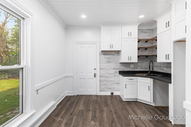 kitchen featuring tasteful backsplash, sink, white cabinets, ornamental molding, and dark wood-type flooring