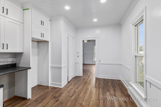 kitchen featuring crown molding, dark wood-type flooring, wooden ceiling, and white cabinets