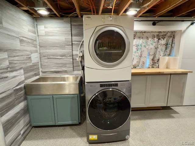 laundry area featuring cabinets and stacked washer / drying machine