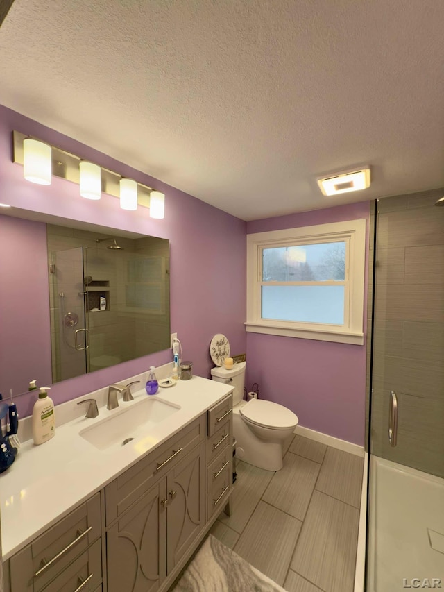 bathroom with vanity, a textured ceiling, a shower with door, and toilet