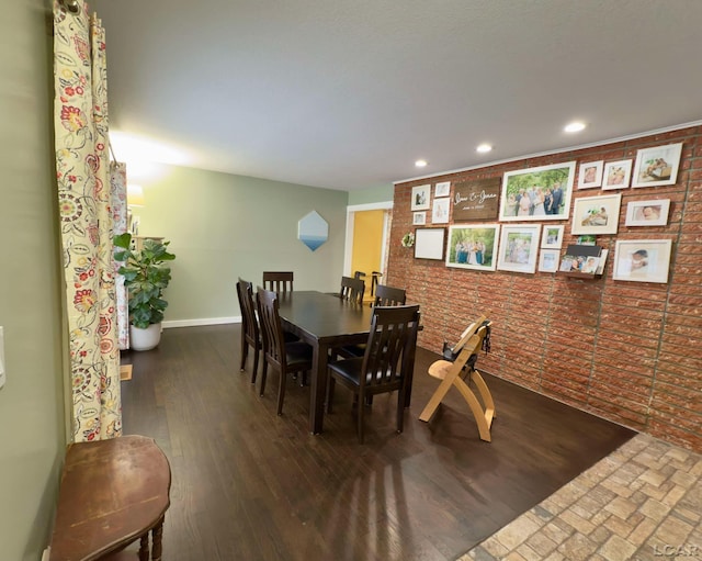 dining room featuring brick wall and dark wood-type flooring