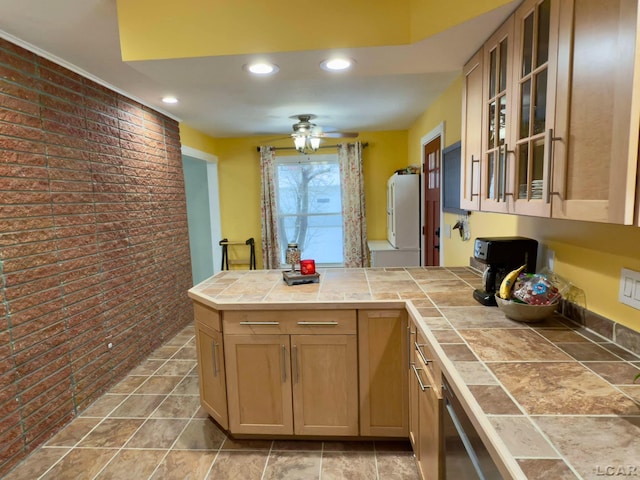 kitchen featuring tile counters, ceiling fan, and brick wall