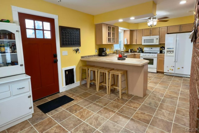 kitchen featuring a breakfast bar, white appliances, light tile patterned floors, kitchen peninsula, and ceiling fan