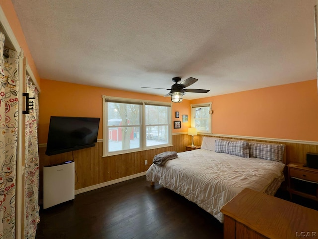 bedroom with wooden walls, dark hardwood / wood-style floors, and a textured ceiling