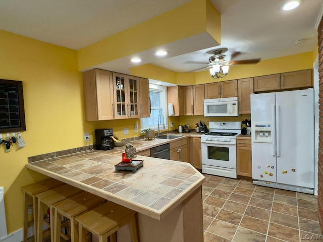 kitchen featuring white appliances, a breakfast bar, kitchen peninsula, and sink