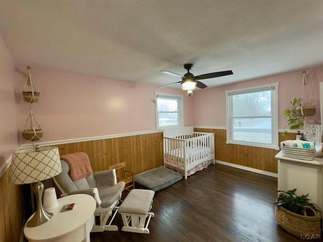 bedroom featuring ceiling fan, dark hardwood / wood-style flooring, and wood walls