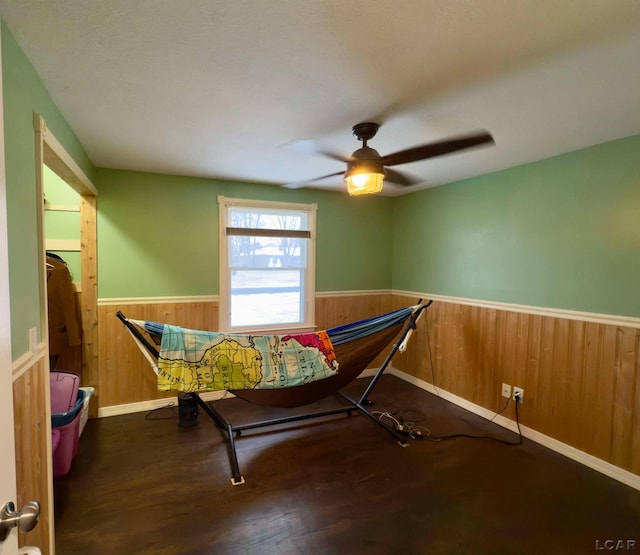 interior space featuring ceiling fan, wood-type flooring, and wood walls