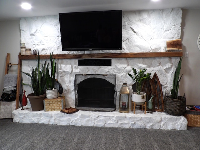 room details featuring a stone fireplace and carpet floors