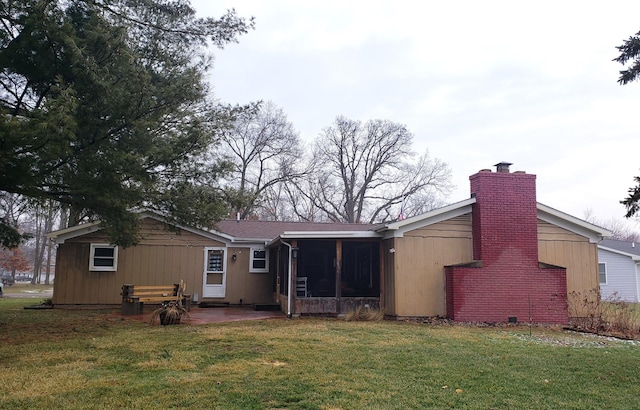 rear view of house featuring a lawn, a sunroom, and a patio