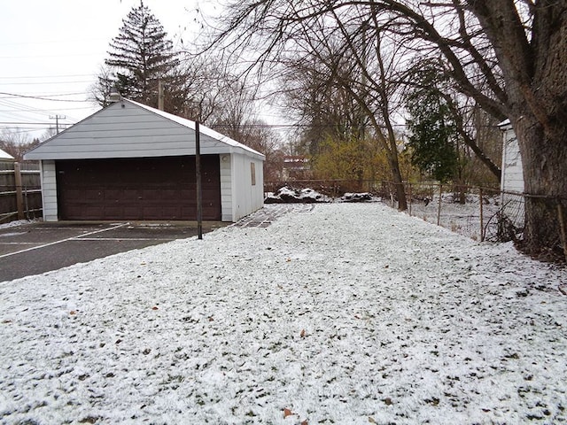 yard layered in snow with an outbuilding and a garage