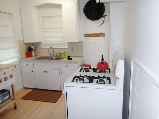 kitchen with white cabinetry, sink, light hardwood / wood-style floors, and white gas range oven